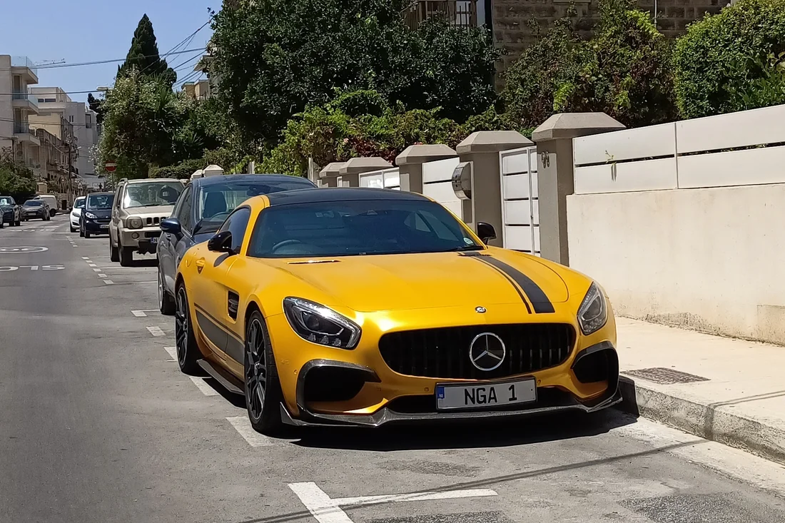 A yellow Mercedes-AMG GT parked on a narrow residential street in Malta beside a palm tree